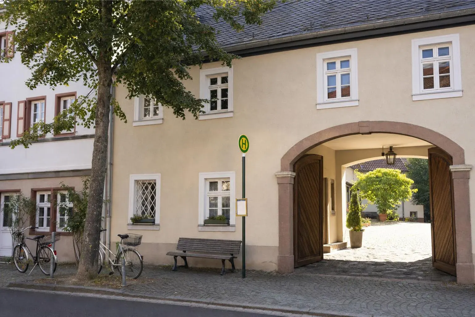 Hausfassade in der Gartenstraße mit offener Toreinfahrt und Bushaltestelle davor